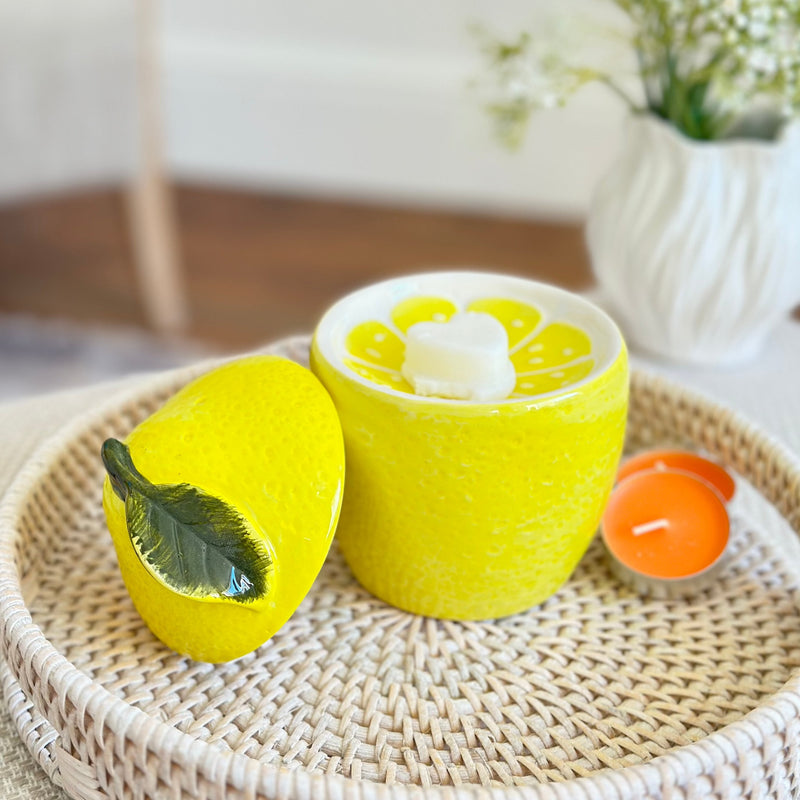 lemon shaped oil burner sat on a round white rattan tray