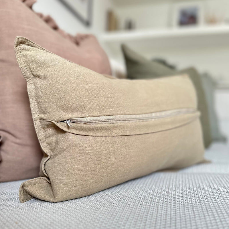 Back of the beige cushion with the fold folded down to show the zip