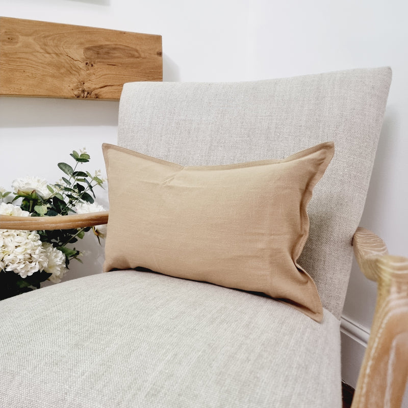 rectangle beige brown cushion sat on a cream armchair.