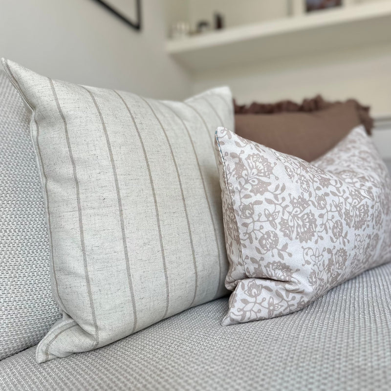 close up of square cream stripe cushion and recatngle cream and floral print cushion