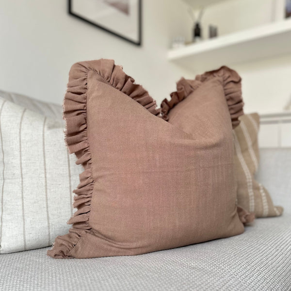 square brown cushion with a ruffled edge sat on a cream sofa