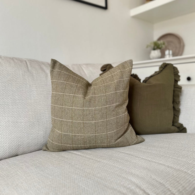 square green tweed cushion sat on a cream sofa