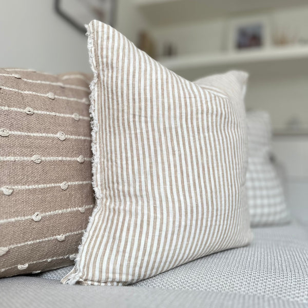 Weathered edge square cream cushion with a vertical beige stripe.