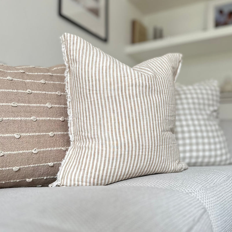 Weathered edge square cream cushion with a vertical beige stripe.