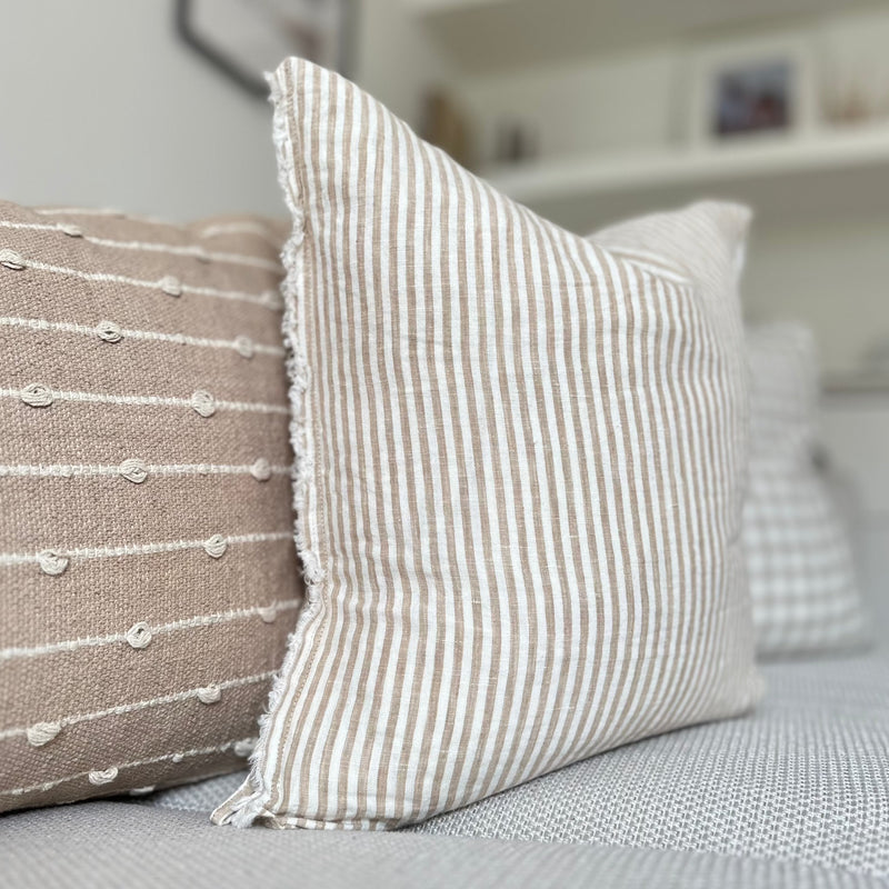 Weathered edge square cream cushion with a vertical beige stripe.