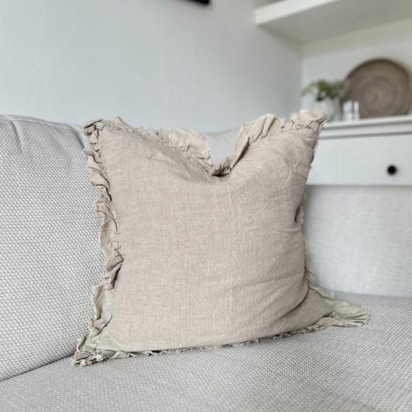 ruffled edge beige linen square cushion on a cream sofa