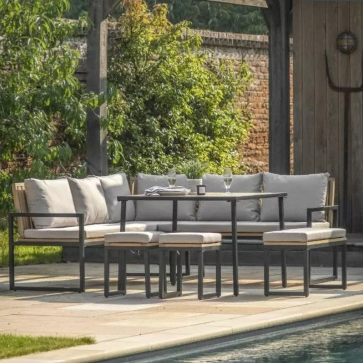 OUTDOOR CORNER DINING SET WITH SQUARE BLACK METAL FRAME, WOODEN SLAT SEATING AND GREY CUSHIONS. DINING TABLE, 2 STOOLS AND 1 BENCH. ALL SAT ON A PATIO BY A POOL