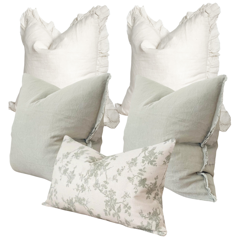 set of 5 cushions. 2 x square cream ruffled edge linen cushions, 2 x weathered edge sage green linen cushions and 1 rectangle cotton cream cushion with an all over sage green floral print. All sat on a white background.