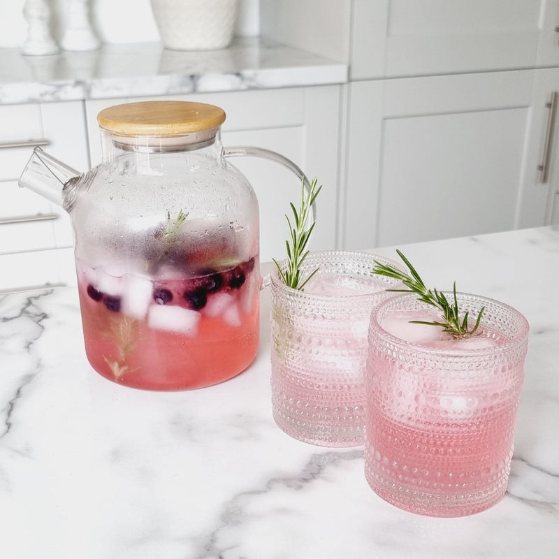 clear glass jars with an all over bobble design filled with pink gin and a sprig of rosemary