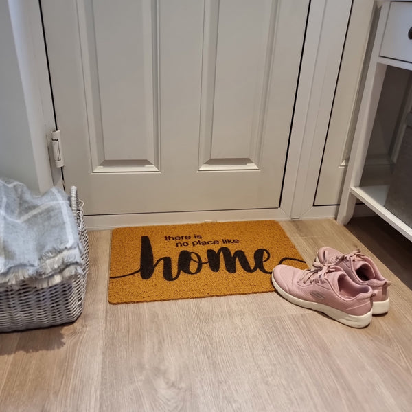 Light brown doormat with there is no place like home printed sat on hallway floor