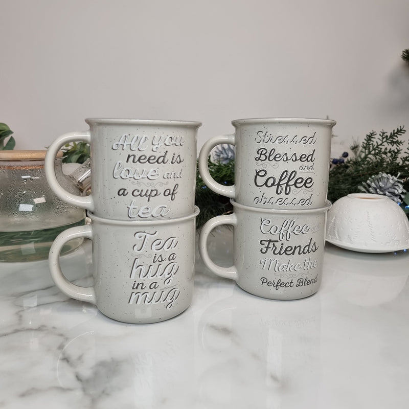 Set of 4 light grey ceramic mugs with coffee lover and tea lover slogans written in white and dark grey, sat on a white kitchen counter