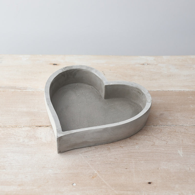 Grey cement love heart shaped dish on a wooden sideboard