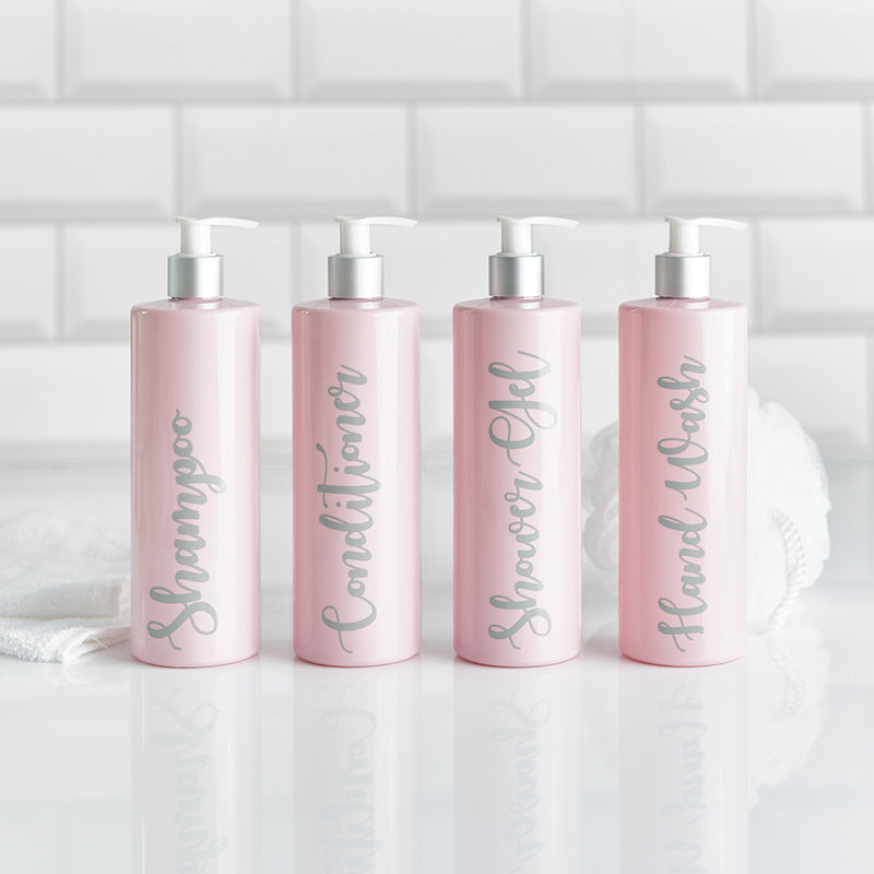 Four pink dispenser bottles with customisable wording in grey for shampoo conditioner shower gel and hand wash in bathroom